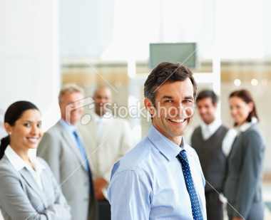stock-photo-10172423-smiling-businessman-with-colleagues-in-the-background
